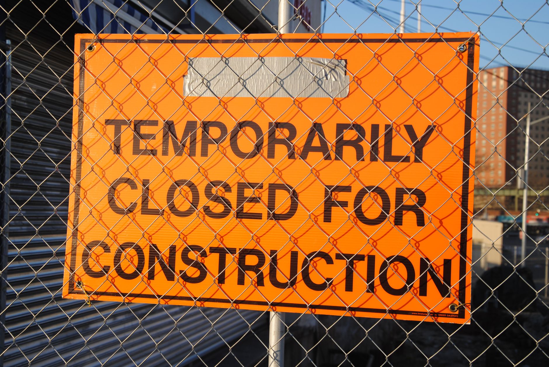 Orange sign behind fence reading 'Temporarily Closed for Construction' at site in Edmond, OK